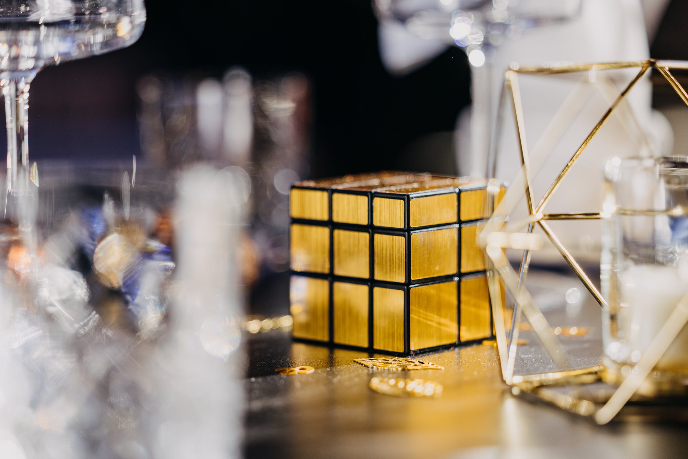 Goldener Spiegelwürfel zwischen Kristallgläsern und goldenen Dekoobjekten