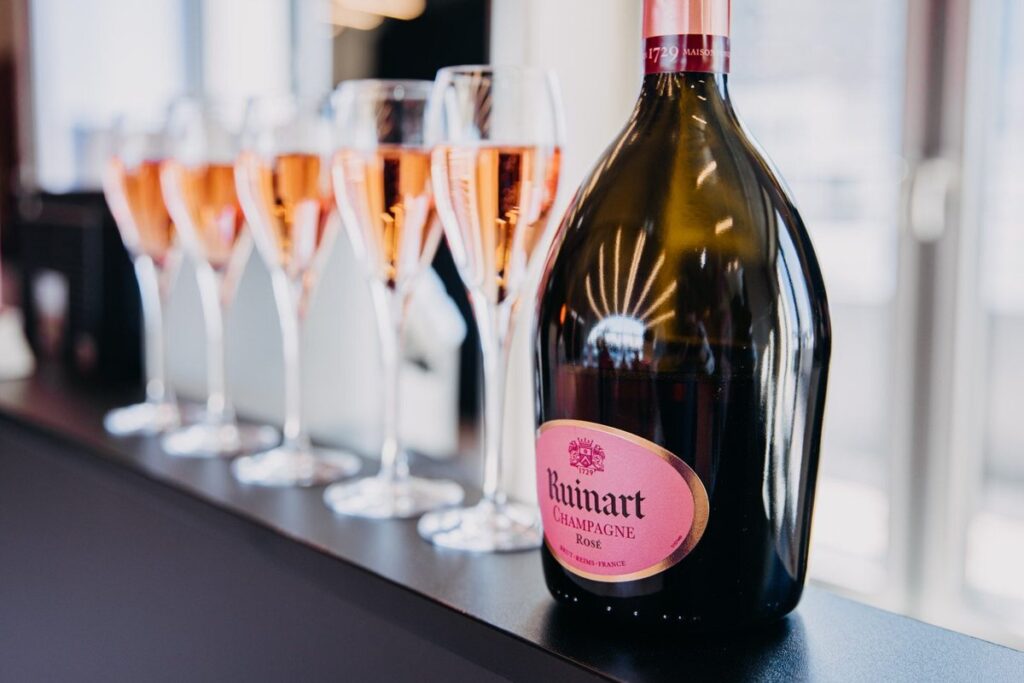 Rosé-Champagner in Sektflöten neben der Flasche auf dem Tresen